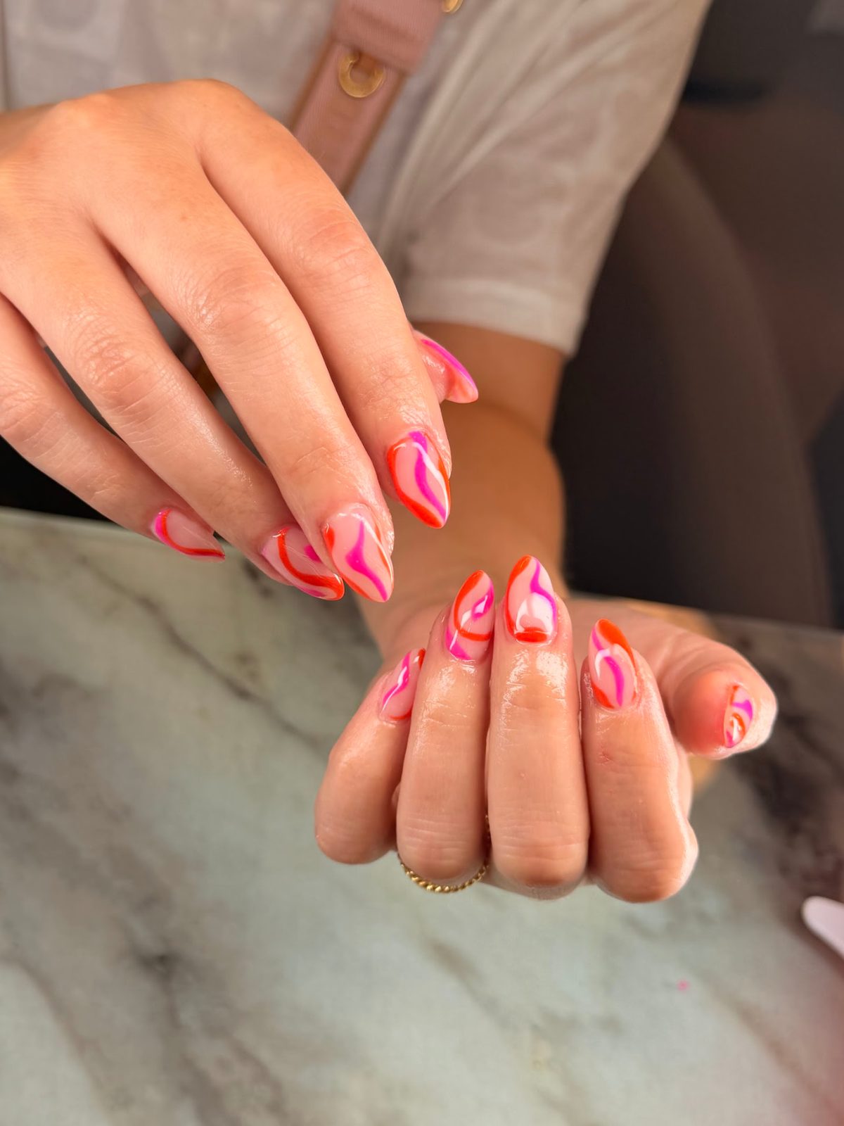 Pink almond nails with vivid red and magenta swirls