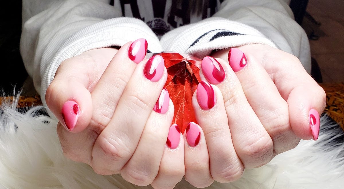 Pink almond nails with deep red swirl accents