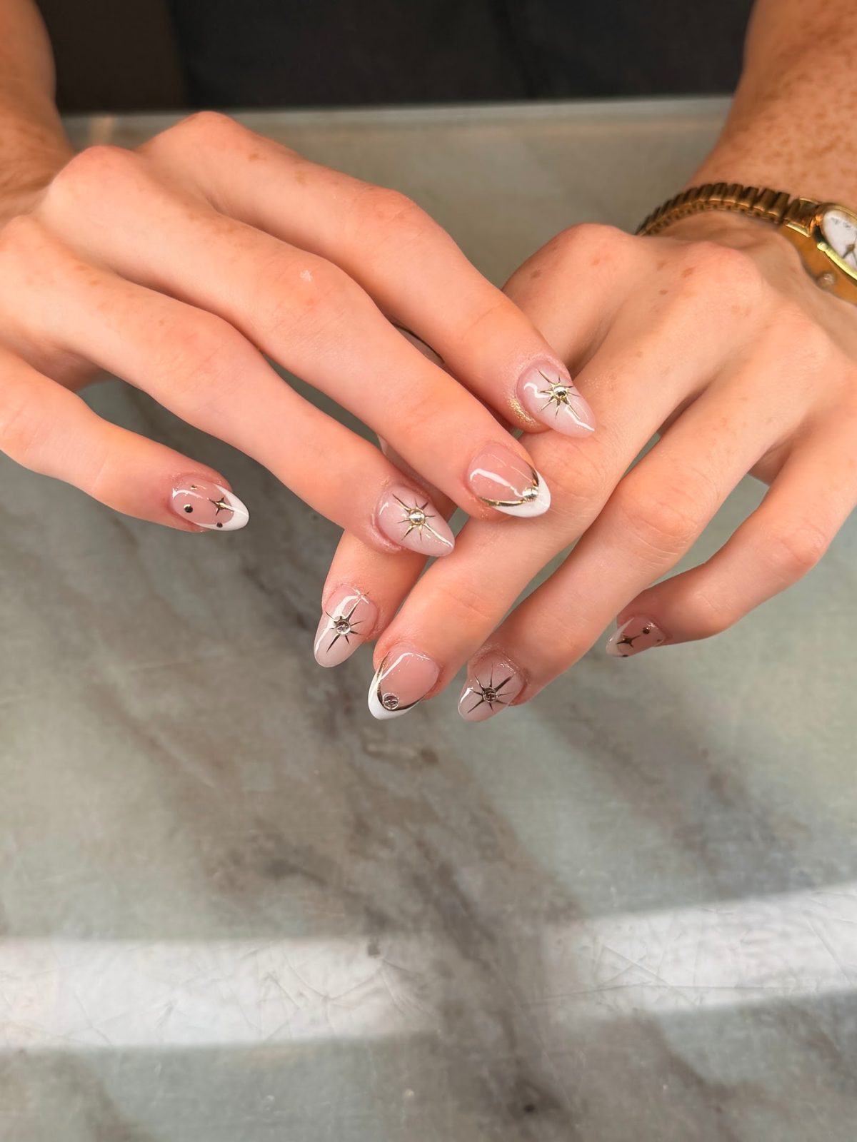Nude almond nails with white tips and starburst charms
